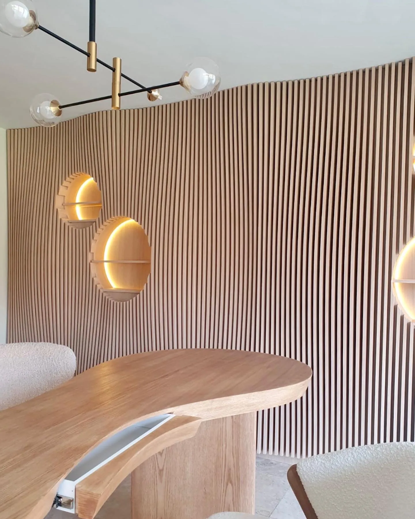 Consultorio Auri — pared de lambín de madera con nichos circulares iluminados