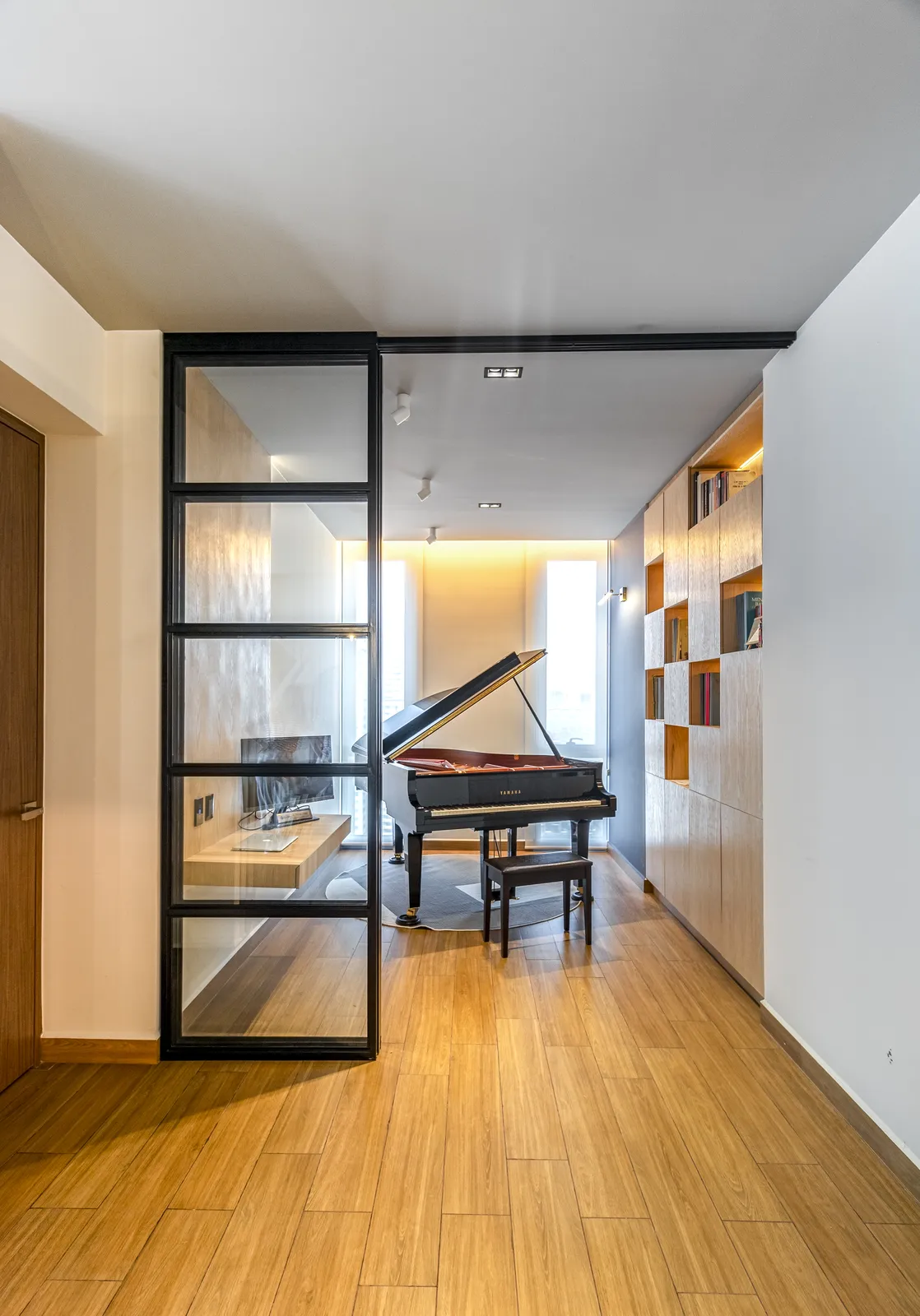 Cuarto de música con piano de cola visto a través de la puerta de cristal