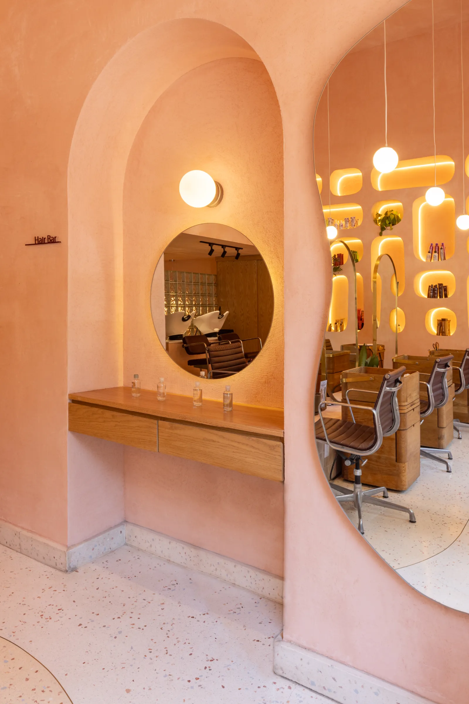 HER Pedregal — arcos y terrazzo con luz cálida en el hair bar