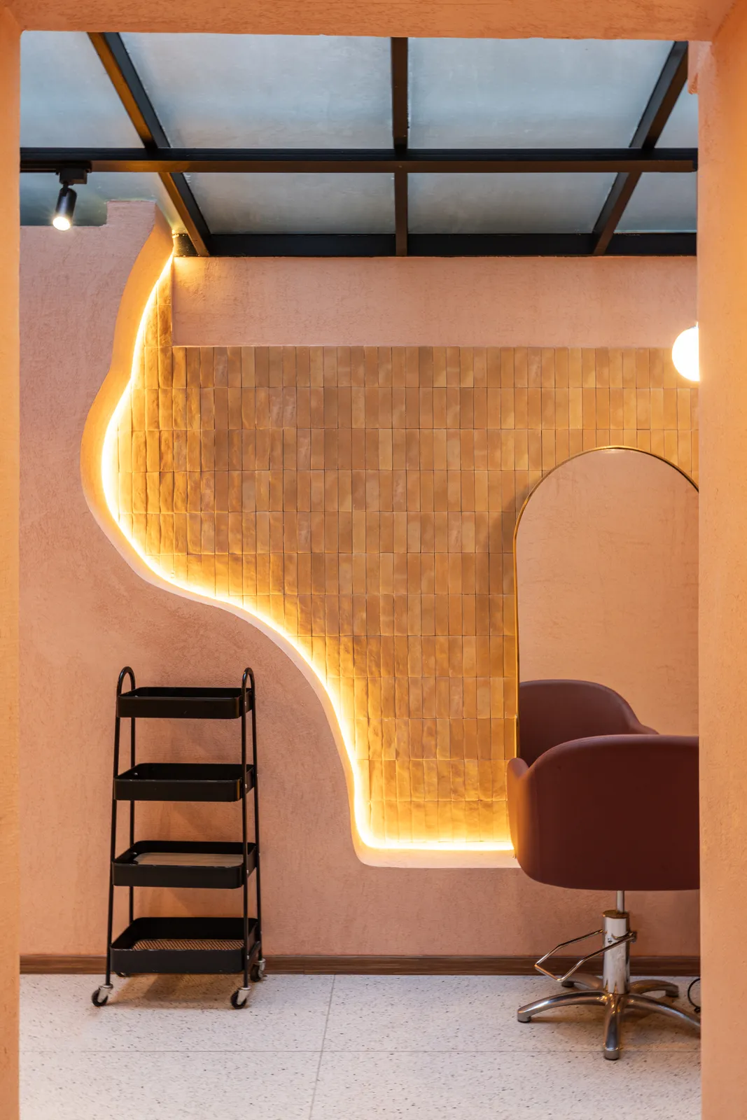Muro curvo de mosaico con iluminación indirecta, formas orgánicas